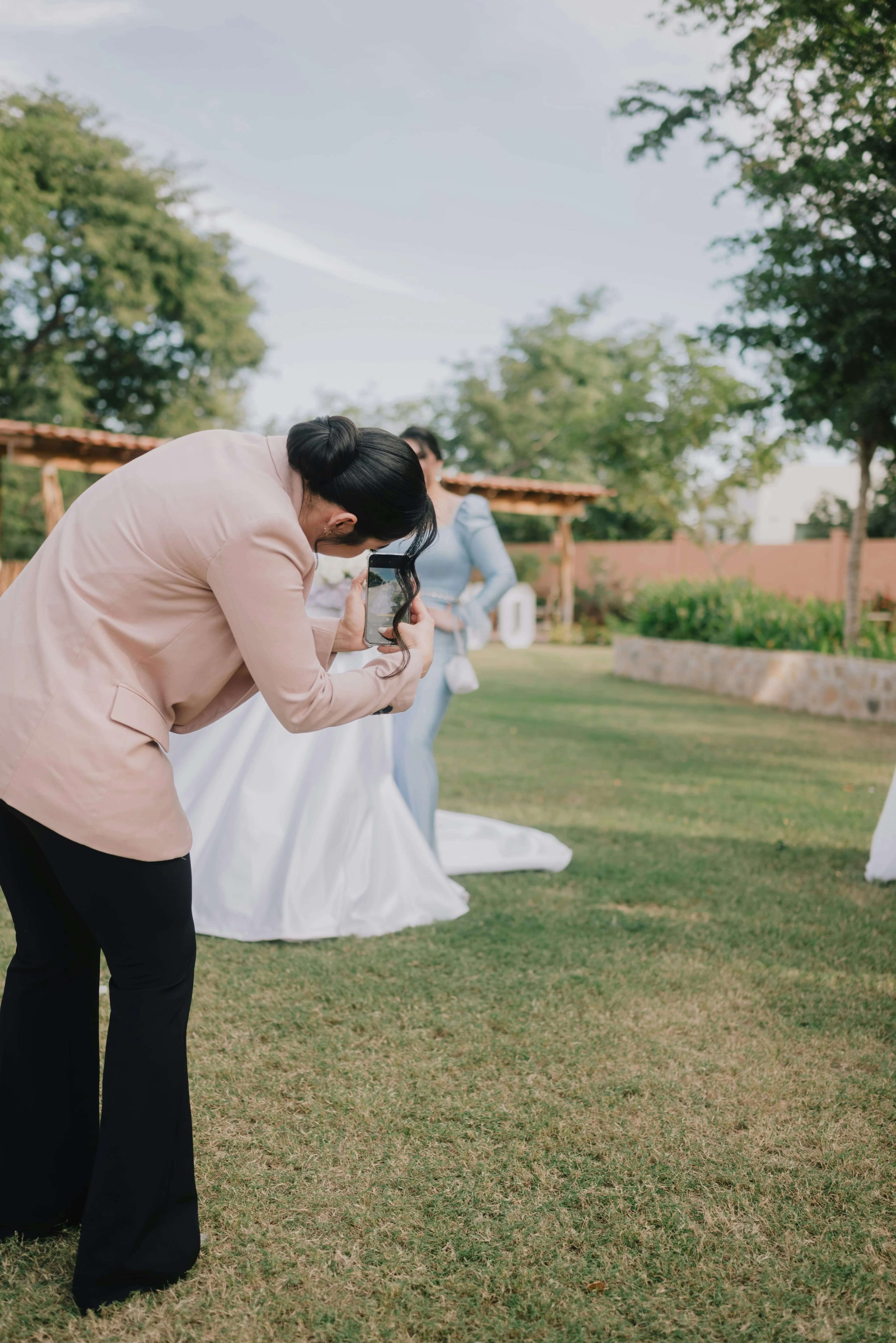 A guest leaning in to photograph the bride with her phone